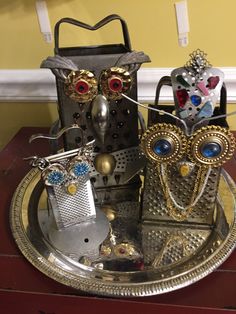 two metal owls sitting on top of a silver plate next to an empty bottle opener