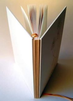 an open book sitting on top of a white table next to a yellow and orange cord