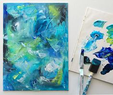 an abstract painting with blue and green colors on it next to a paintbrushes