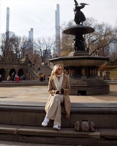 a woman sitting on the steps in front of a fountain