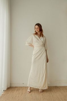 a woman in a white dress standing against a wall