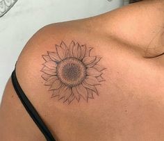 a sunflower tattoo on the back of a woman's upper arm and shoulder