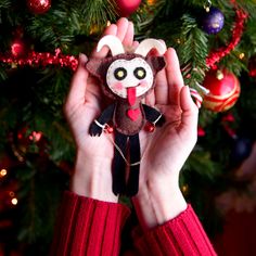 a person holding a stuffed animal in front of a christmas tree with ornaments on it