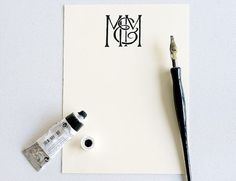 a white sheet of paper with black ink next to a paintbrush and acrylic tube