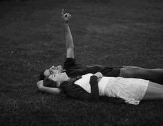 a man and woman laying on the grass with their arms in the air while holding a frisbee