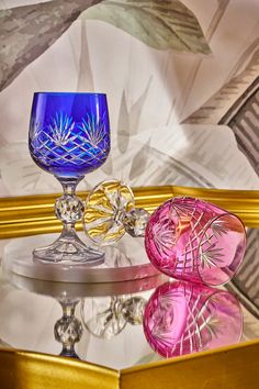 three glass goblets sitting on top of a mirrored table next to each other