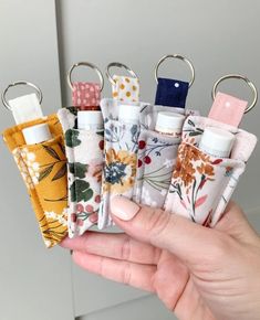 a person holding four small keychains in their hand, each with different designs on them