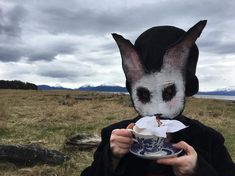 a person wearing a bunny mask and holding a cup in front of their face,