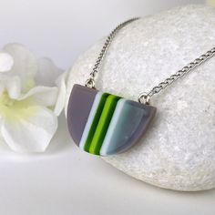 One of a kind handmade fused glass pendant. Simple and elegant modern minimalist style Transparent green gray and with stripes with geometric shape. Size: 30mm x 20mm x 6mm. Cast silver necklace attachments. Incorporates Bullseye opal and transparent glass. Sculpted by hand and fused multiple times. Includes nickle free hypoallergenic 18 inch attached chain. Message anytime with questions. -Sean Modern Green Necklace As Gift, Modern Green Necklace For Gift, Modern Green Necklace As A Gift, Modern Green Necklace With Round Pendant, Modern Green Round Pendant Necklace, Minimalist Green Jewelry With Recycled Glass, Minimalist Green Glass Jewelry, Modern Silver Glass Necklaces, Modern Multicolor Glass Jewelry