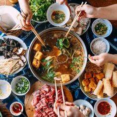 several people are eating food from bowls on a table with chopsticks in their hands