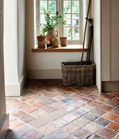 a window sill with potted plants in it and a basket on the floor