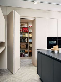 a kitchen with white cabinets and black counter tops next to an open pantry door in the middle