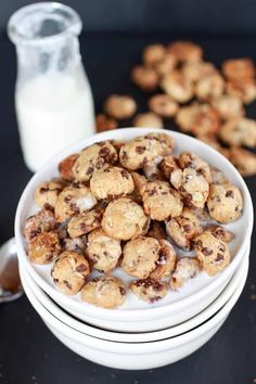 chocolate chip cookies in a white bowl next to a glass of milk