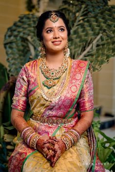 a woman in a yellow and pink dress sitting down with her hands clasped on her chest