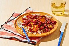 a yellow plate topped with beans and rice next to a glass of water on top of a wooden table