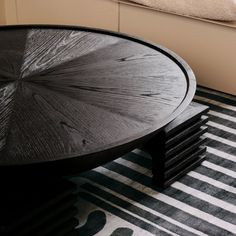 a black coffee table sitting on top of a striped rug next to a white window