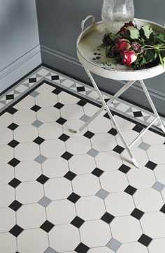 a white and black tiled floor with flowers on the tray next to it in a bathroom