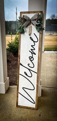 a sign that says welcome hanging from the side of a building with a bow on it