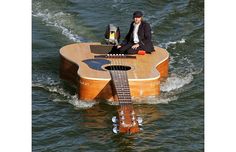 a man sitting on top of a guitar in the water with caption that reads, guitarists leaving work on friday like