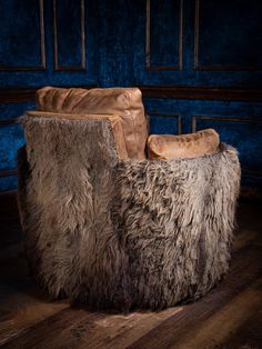 a brown leather chair sitting on top of a wooden floor next to a blue wall