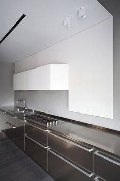 a kitchen with white cabinets and stainless steel counter tops, along with a stove top oven