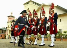 a group of men in uniform standing next to each other with a dog on a leash