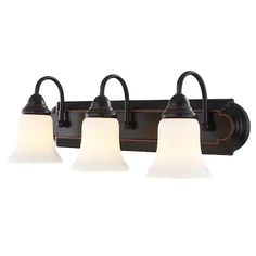 three light bathroom fixture in an antique bronze finish with white glass shades on the sides