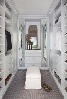 a walk in closet filled with lots of white drawers and shelves next to a mirror