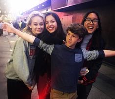 three girls and one boy are posing for the camera with their arms around each other