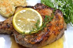 a close up of a plate of food with meat and lemon wedges on it