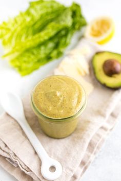 an avocado and some lettuce on a towel next to a spoon