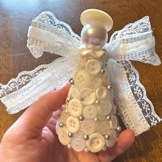 a hand is holding a small white christmas tree ornament with buttons on it