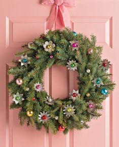 a christmas wreath hanging on a pink door