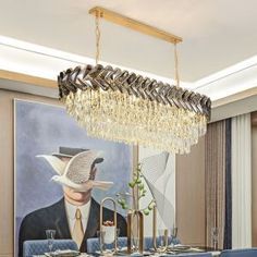 a chandelier hanging over a dining room table with blue chairs and a painting on the wall