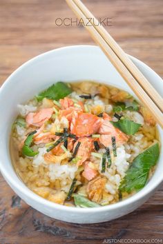 a white bowl filled with rice and vegetables next to chopsticks