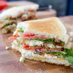 a cut in half sandwich sitting on top of a wooden cutting board