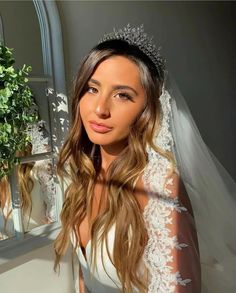 a woman in a wedding dress and veil posing for a photo next to a mirror