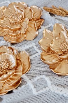 three gold flowers are sitting on a lace tablecloth