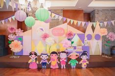 some paper cutouts are sitting on the floor in front of a backdrop with flowers and bunting