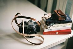 a camera sitting on top of a table next to some books and a leather bag