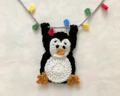 a black and white penguin with multicolored beads on it's head hanging from a string