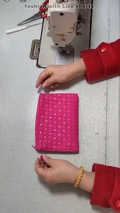 the woman is working on her sewing machine with pink material in front of her and another hand holding a small piece of fabric