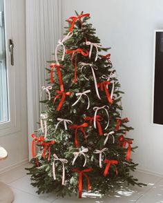 a decorated christmas tree with red and white ribbons