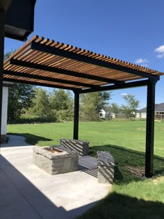 a covered patio with benches and grass in the background