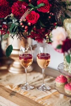 two glasses of wine on a table with flowers