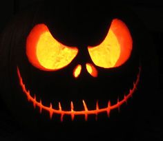 a jack o lantern pumpkin with glowing eyes and fangs on it's face, lit up in the dark