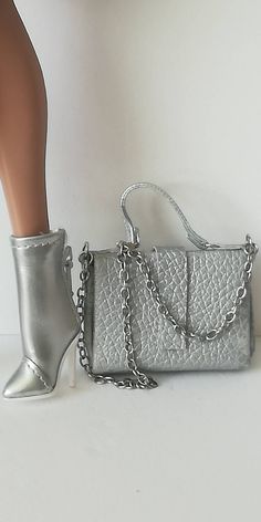 a doll is standing next to a silver purse