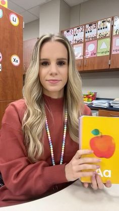 a woman sitting at a table with a book in front of her and an apple on the cover