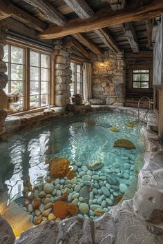 an indoor swimming pool with rocks in the water and windows above it, along with stone walls