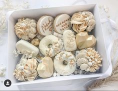 a box filled with assorted donuts on top of a white cloth covered table